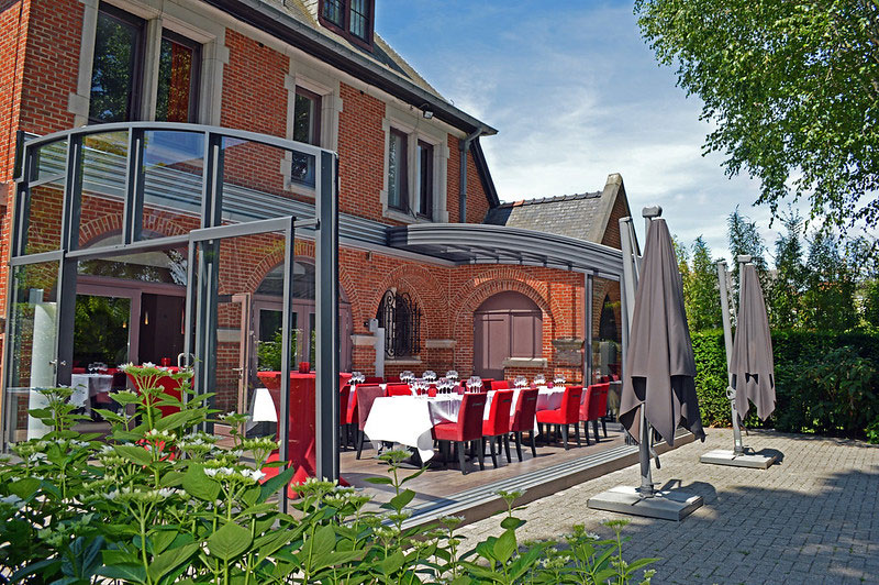 An outdoor restaurant area with a retractable enclosure open on a sunny day